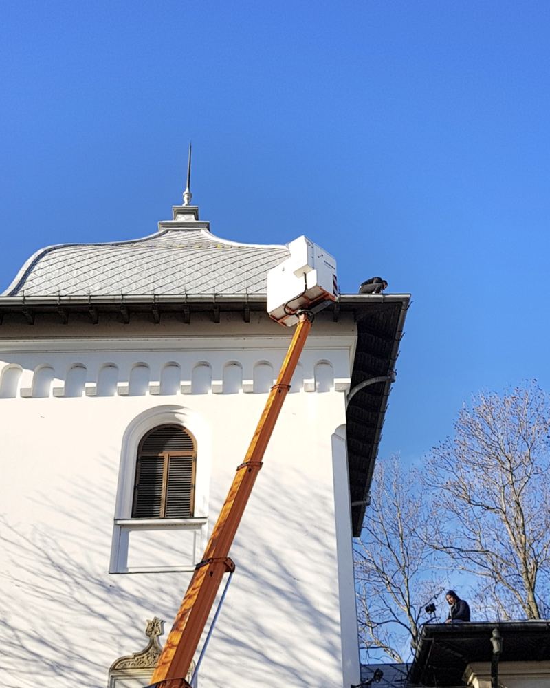 Montaj din nacela la streasina Palatului Cotroceni, cu un al doilea om lucrand pe acoperis